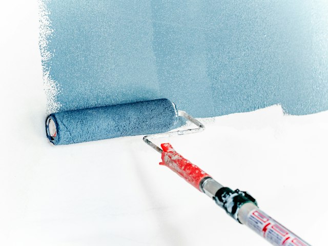 A roller laying fresh paint on a wall